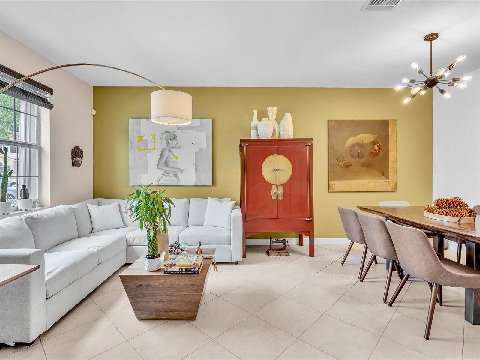 A living and dining room with a yellow accent wall, white sofa, and wooden furniture — 5331 Ashley River Road, West Palm Beach FL 33417, WEST PALM BEACH, FL