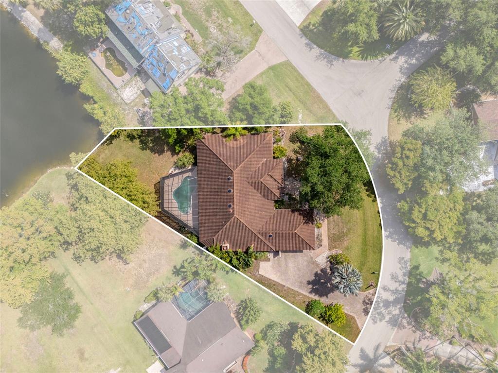 An aerial view shows a house with a brown tile roof, pool, and driveway — 7214 HENDRY CREEK DRIVE, FORT MYERS, FL