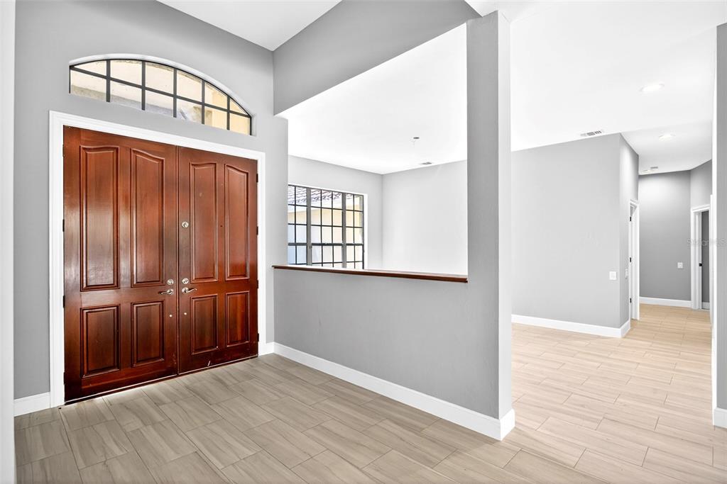 An entryway features double wood doors, a transom window, and light-colored tile flooring — 7214 HENDRY CREEK DRIVE, FORT MYERS, FL