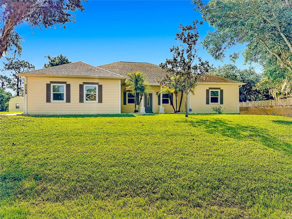 A single-story, light yellow house with a hip roof sits on a large grassy lot — 2155 BARRATT COURT, ST CLOUD, FL
