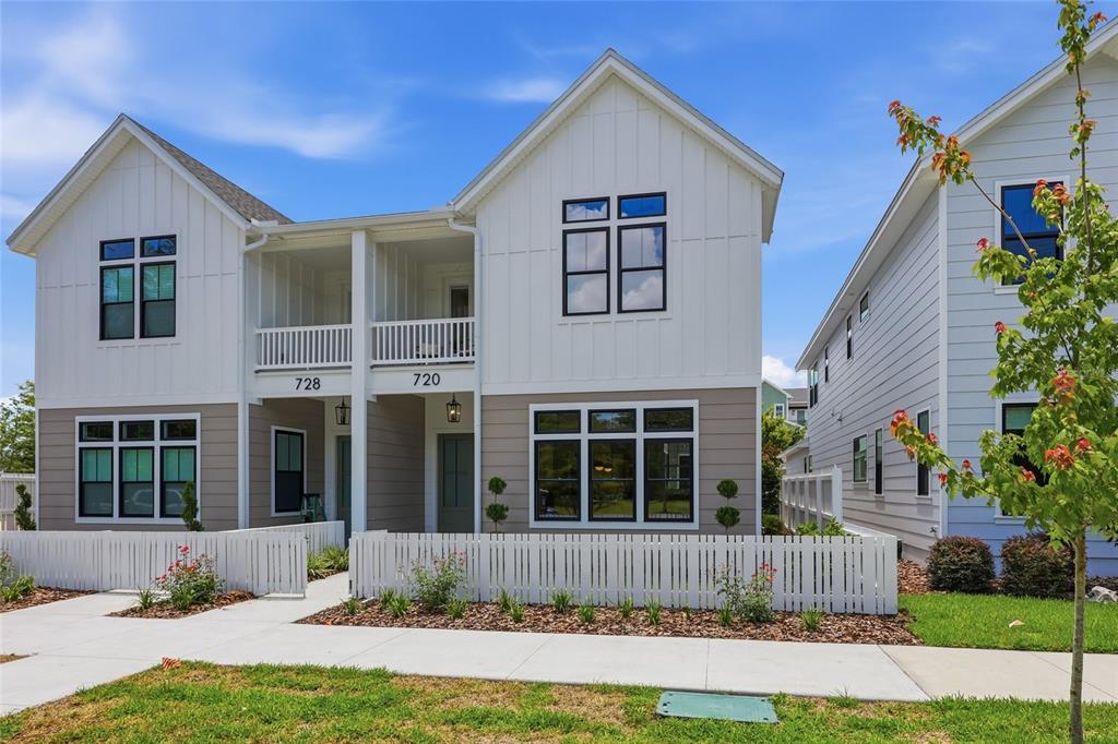 A two-story duplex features white vertical siding, tan horizontal siding, and a white picket fence — 720 SW 131 STREET, NEWBERRY, FL