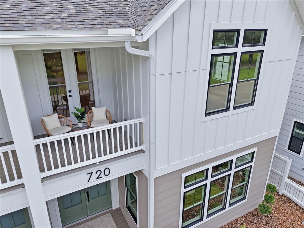 An exterior view of a two-story house featuring a balcony, white siding, and green doors — 720 SW 131 STREET, NEWBERRY, FL