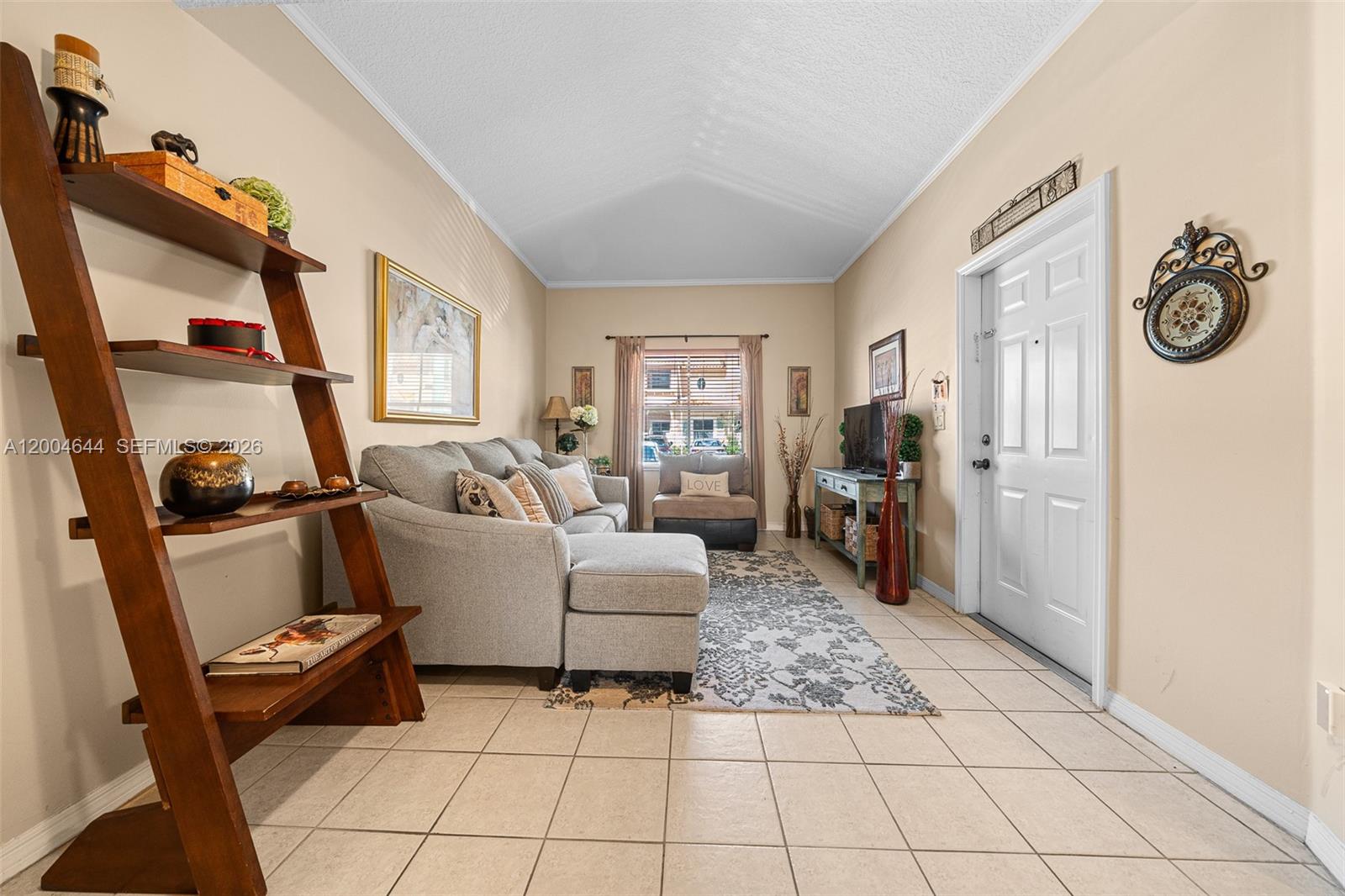 A living room features a gray sectional sofa, a wooden ladder shelf, and tile flooring — 4948 Tradewinds Ter # 504, Dania Beach FL 33312, DANIA BEACH, FL