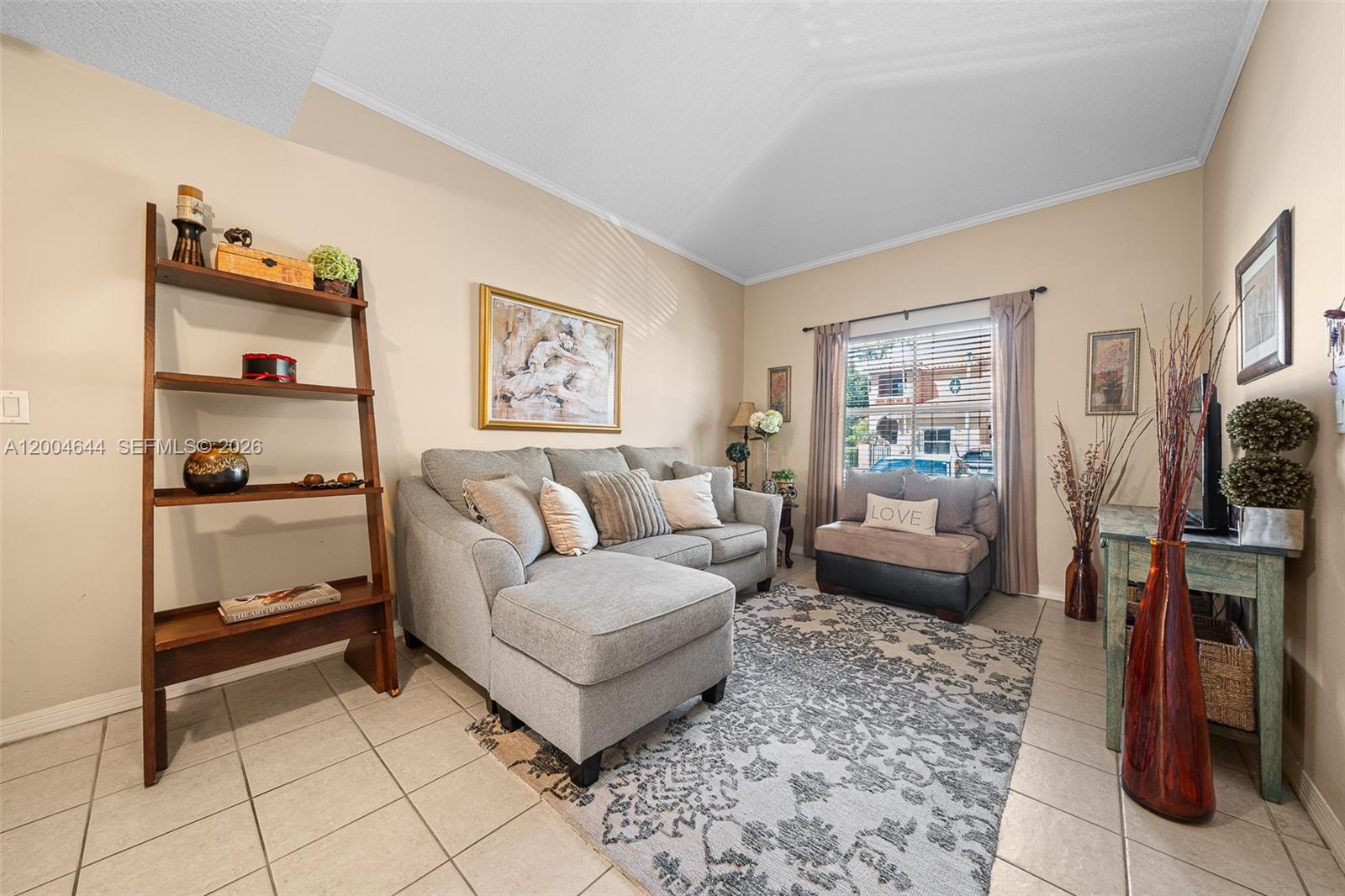 A living room features a gray sectional sofa, a ladder shelf, and a patterned area rug — 4948 Tradewinds Ter # 504, Dania Beach FL 33312, DANIA BEACH, FL