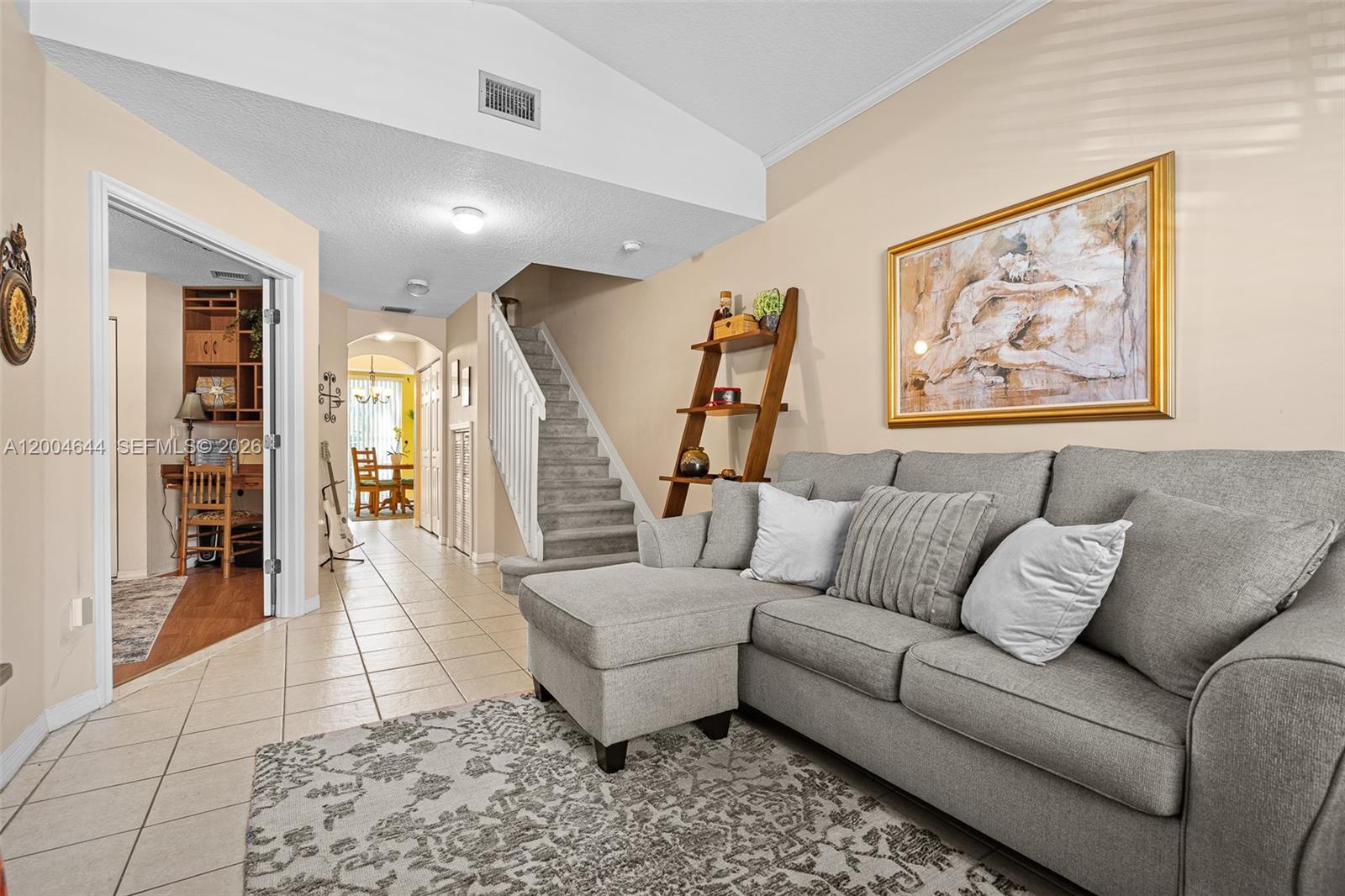 A living room features a gray sectional sofa, a staircase, and a view into a dining area — 4948 Tradewinds Ter # 504, Dania Beach FL 33312, DANIA BEACH, FL