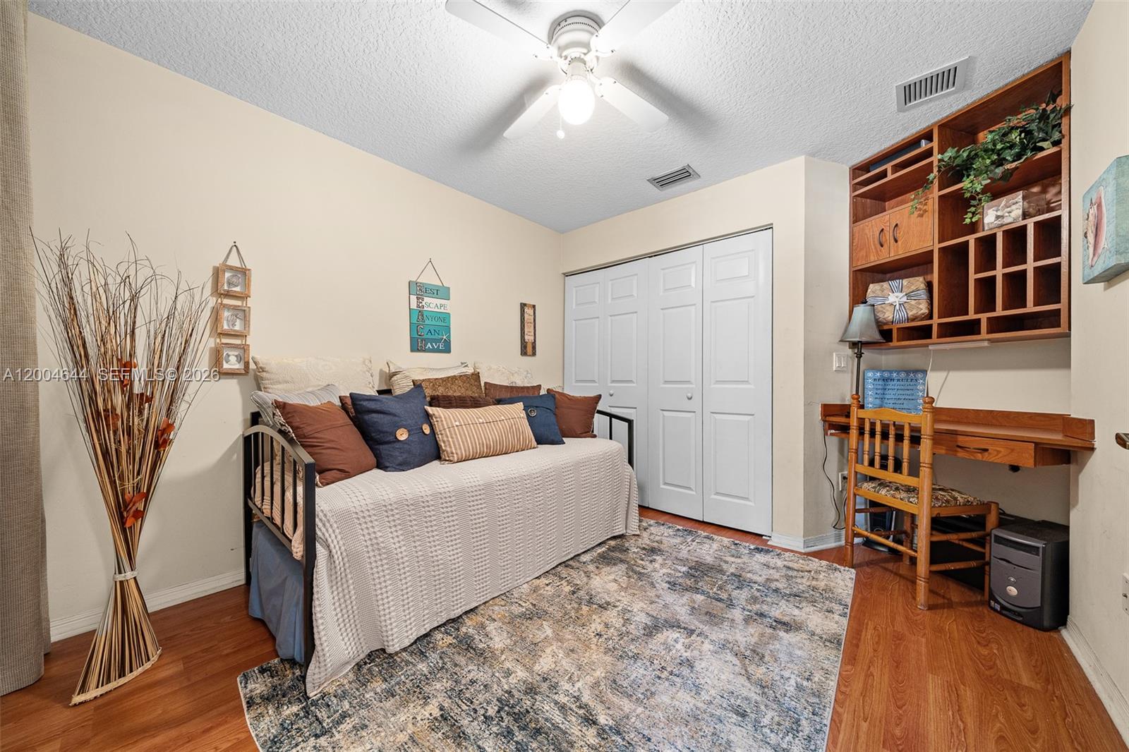 A bedroom features a daybed, a built-in wooden desk with shelving, and wood-look flooring — 4948 Tradewinds Ter # 504, Dania Beach FL 33312, DANIA BEACH, FL