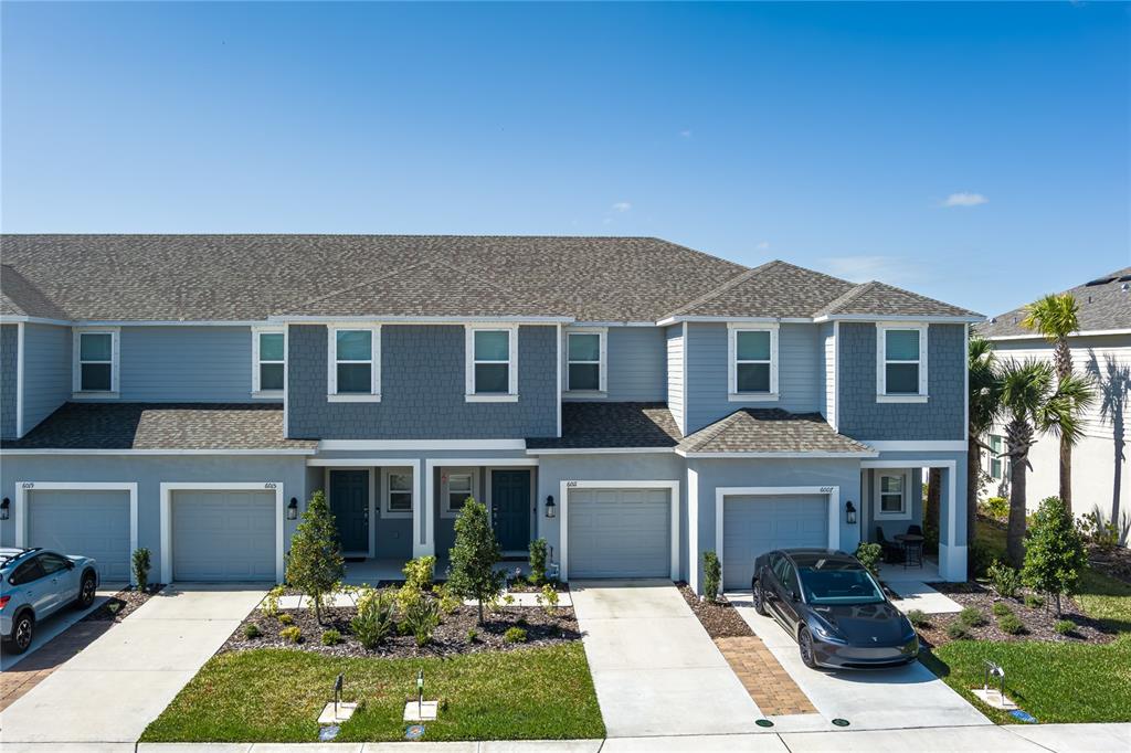 An exterior view of a multi-unit townhouse complex with gray siding and attached garages — 6011 WHETSTONE COURT, PALMETTO, FL