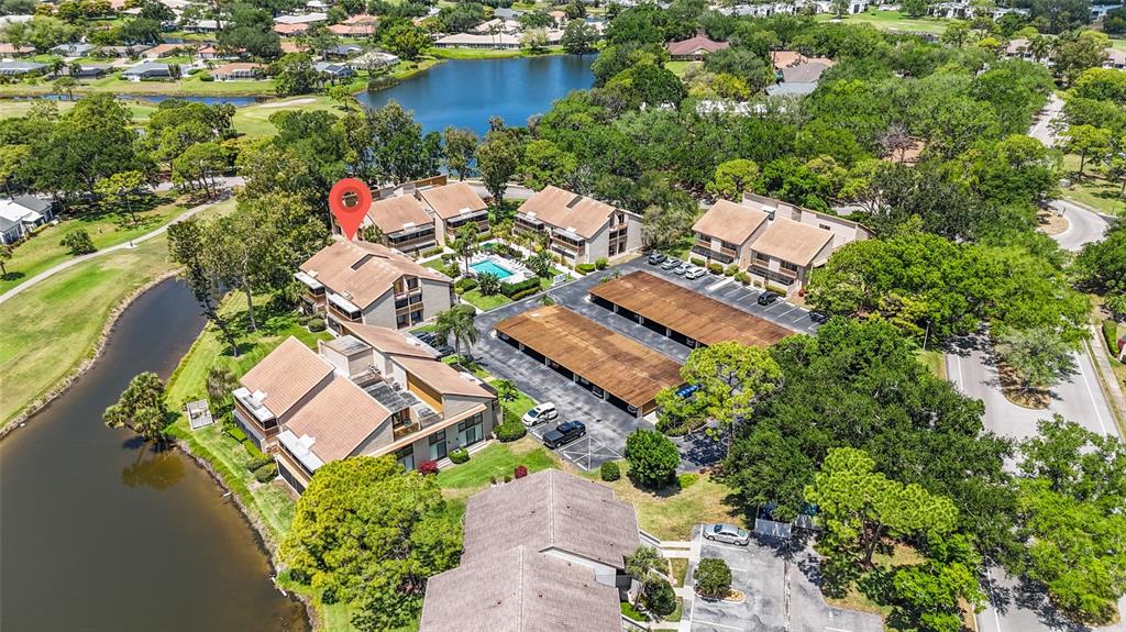 An aerial view shows multi-story residential buildings with brown roofs near a lake and trees — 3033 WILLOW GREEN UNIT 10, SARASOTA, FL
