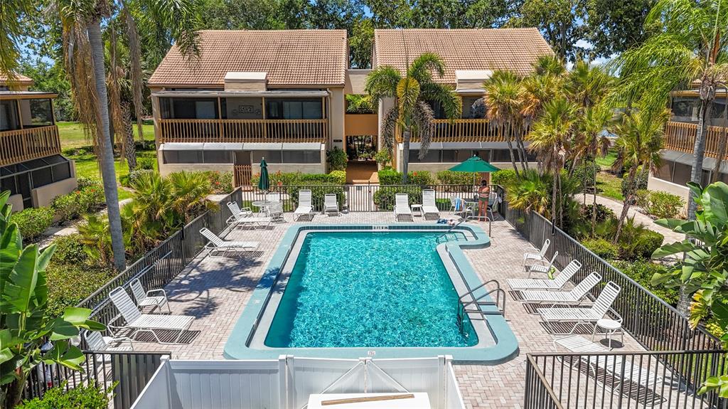 An outdoor swimming pool surrounded by lounge chairs and palm trees in a residential complex — 3033 WILLOW GREEN UNIT 10, SARASOTA, FL