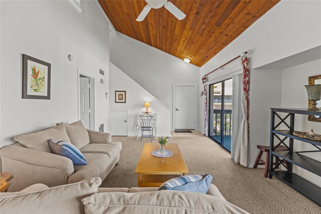 A living room features a vaulted wood-paneled ceiling, beige carpet, and a sliding glass door — 3033 WILLOW GREEN UNIT 10, SARASOTA, FL