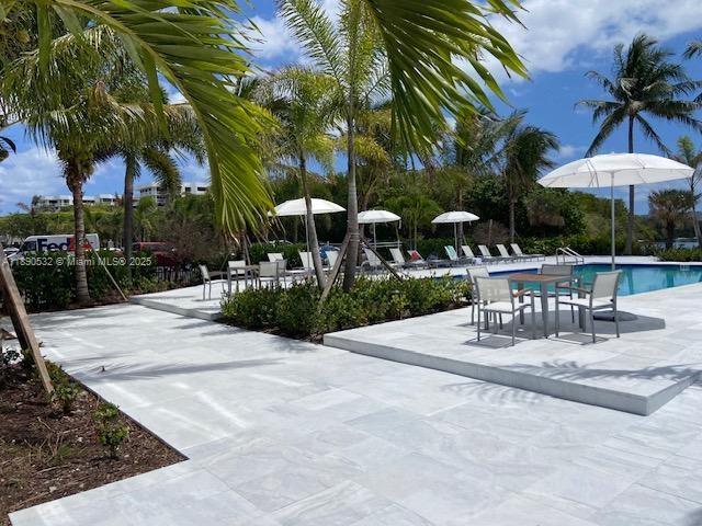 A paved pool deck features lounge chairs, umbrellas, and palm trees under a blue sky — 2560 S Ocean Blvd # 312, Palm Beach FL 33480, PALM BEACH, FL
