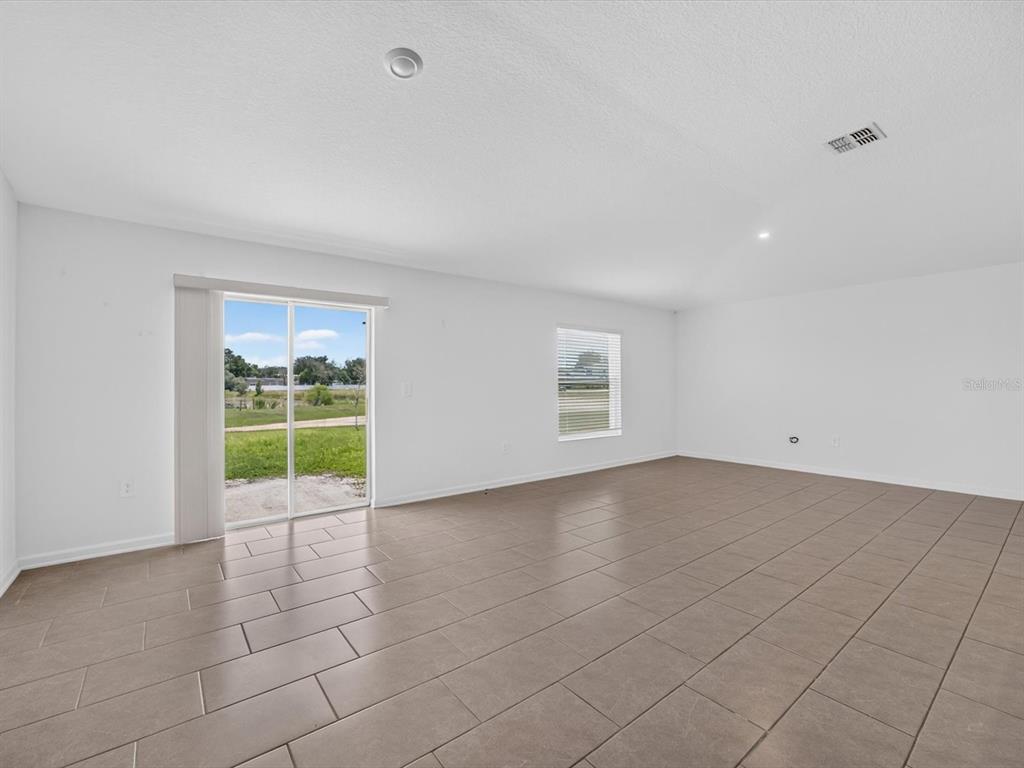 An empty room with white walls, tile flooring, a sliding glass door, and one window — 1119 JAMES PAUL ROAD, DAVENPORT, FL
