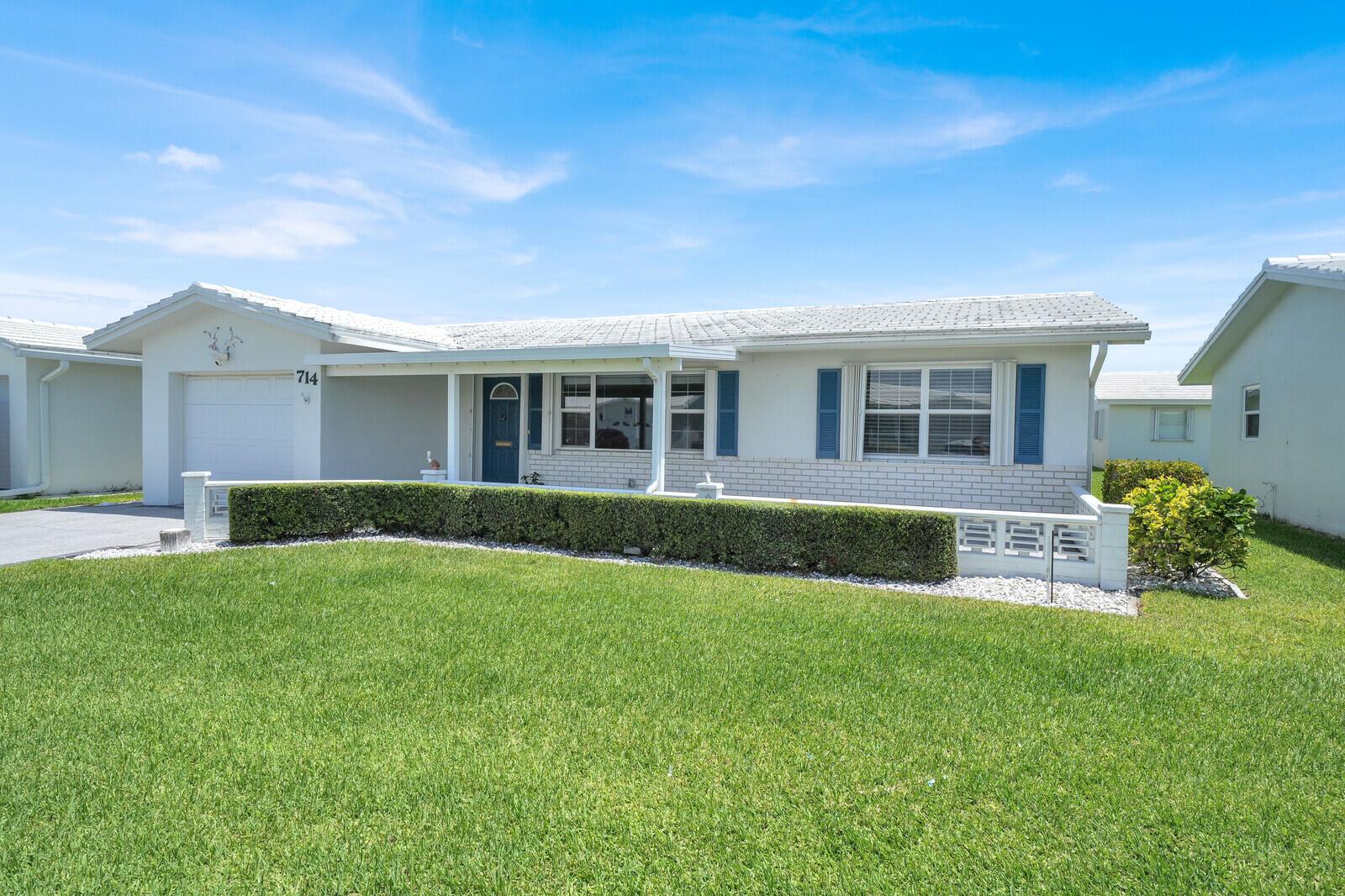 A single-story house with a white exterior, blue shutters, a garage, and a manicured hedge — 714 SW 16th Street, Boynton Beach FL 33426, BOYNTON BEACH, FL