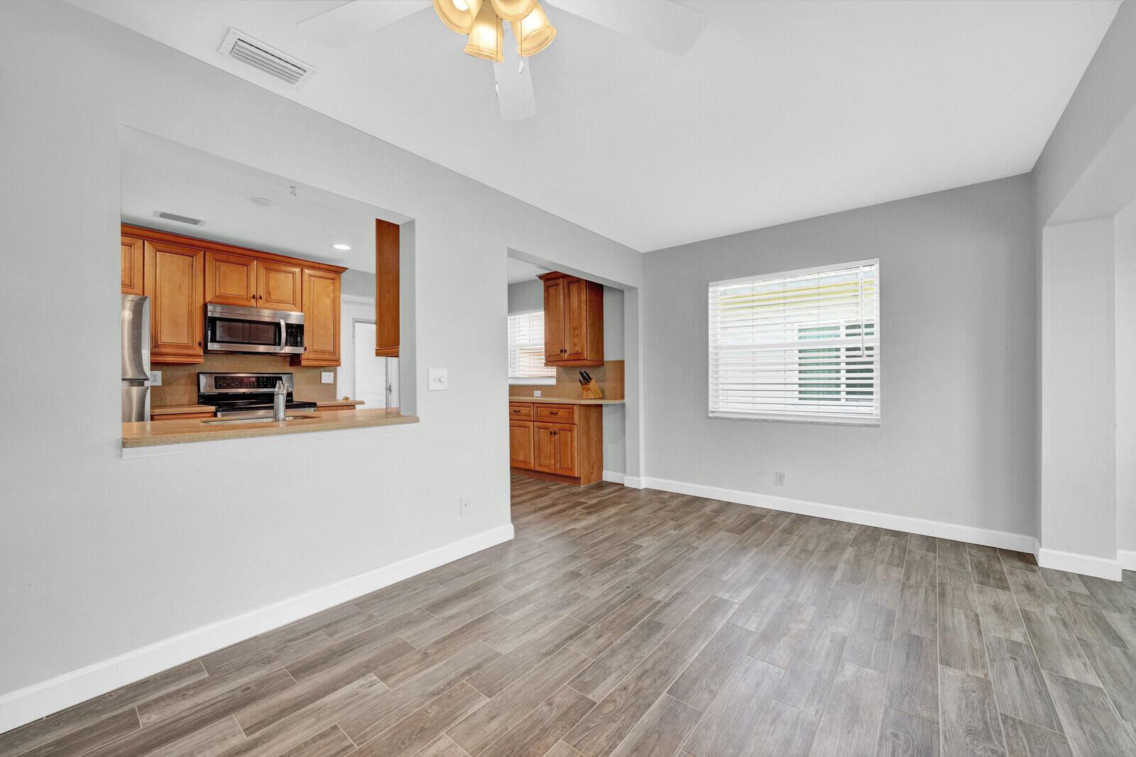 A dining area with wood-look tile flooring, light gray walls, and a kitchen pass-through window — 714 SW 16th Street, Boynton Beach FL 33426, BOYNTON BEACH, FL