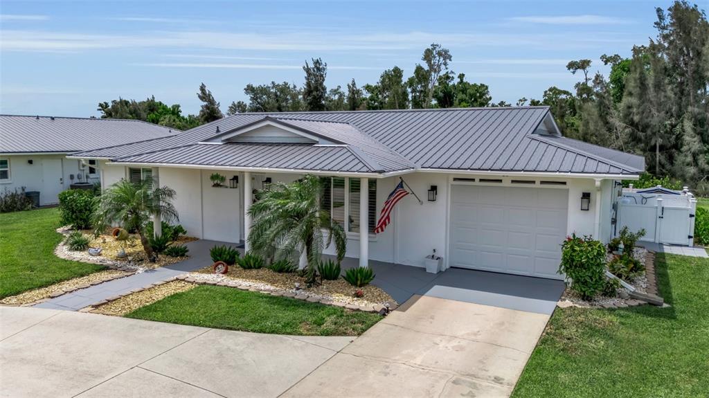 A single-story house with a gray metal roof, white exterior, and an attached garage — 720 S GONDOLA DRIVE, VENICE, FL