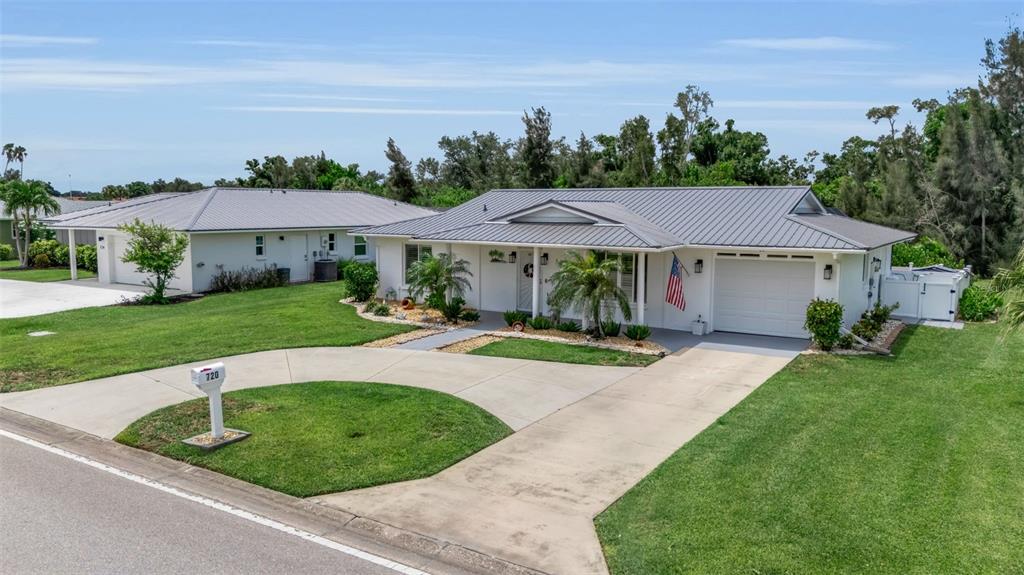 A single-story house with a metal roof, a concrete driveway, and a front lawn — 720 S GONDOLA DRIVE, VENICE, FL