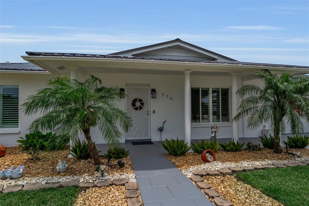The exterior of a single-story house features a covered porch, palm trees, and gravel landscaping — 720 S GONDOLA DRIVE, VENICE, FL