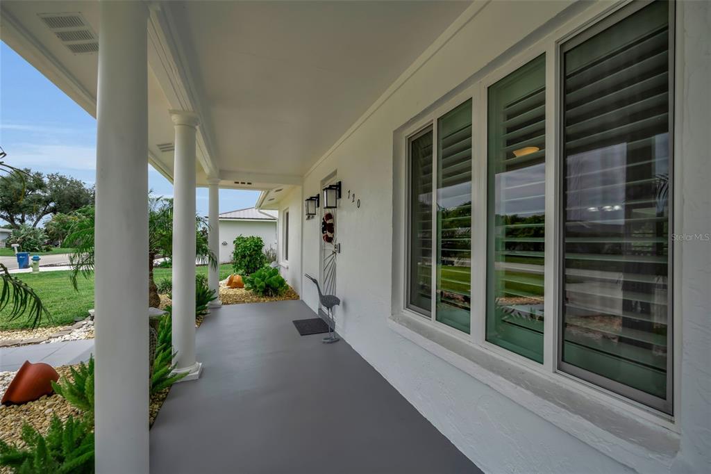 A covered front porch with white columns, a gray floor, and a large window — 720 S GONDOLA DRIVE, VENICE, FL