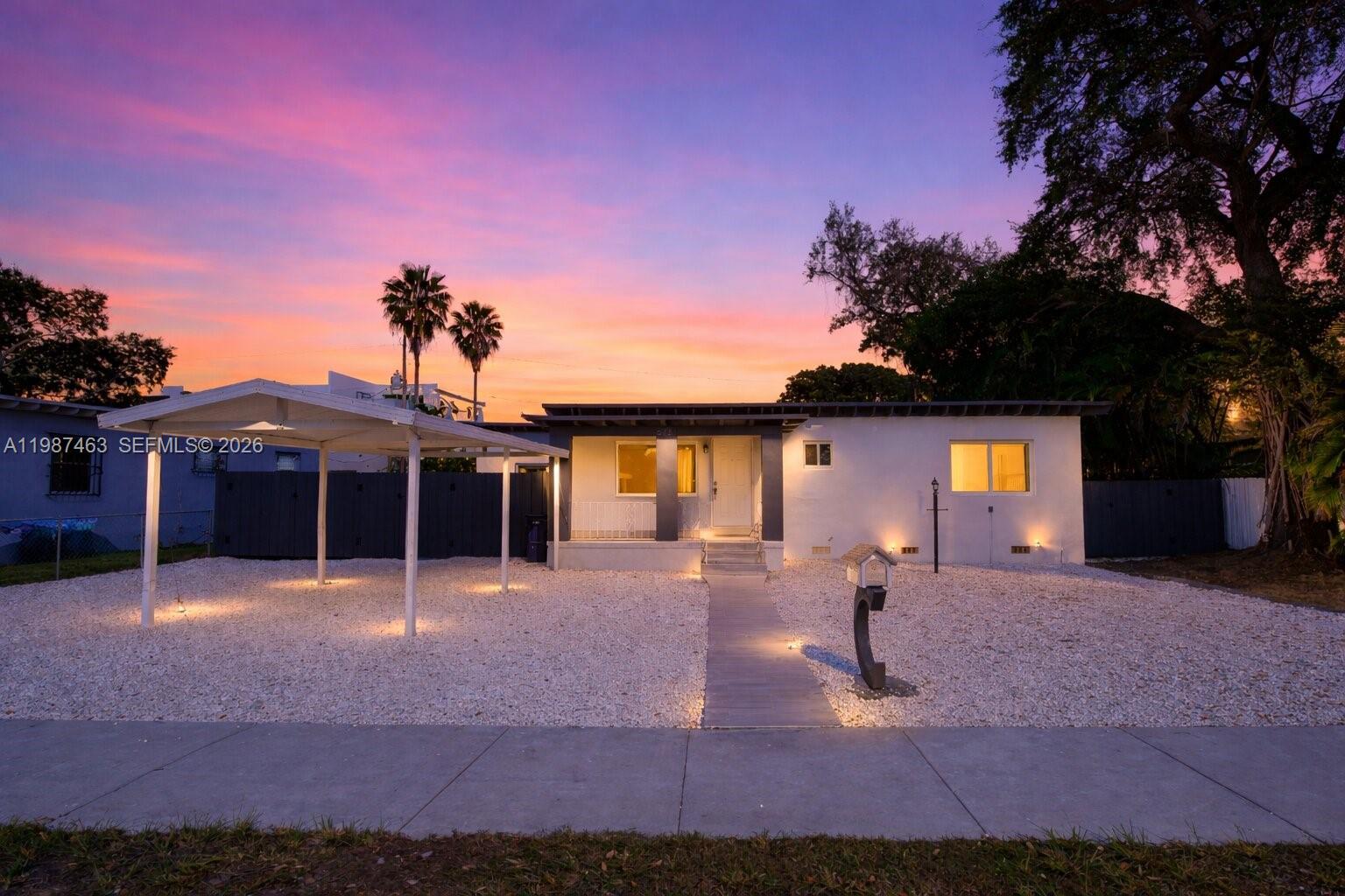 A single-story house with a white gravel front yard and a covered carport at dusk — 5731 SW 62nd Ter, Miami FL 33143, MIAMI, FL