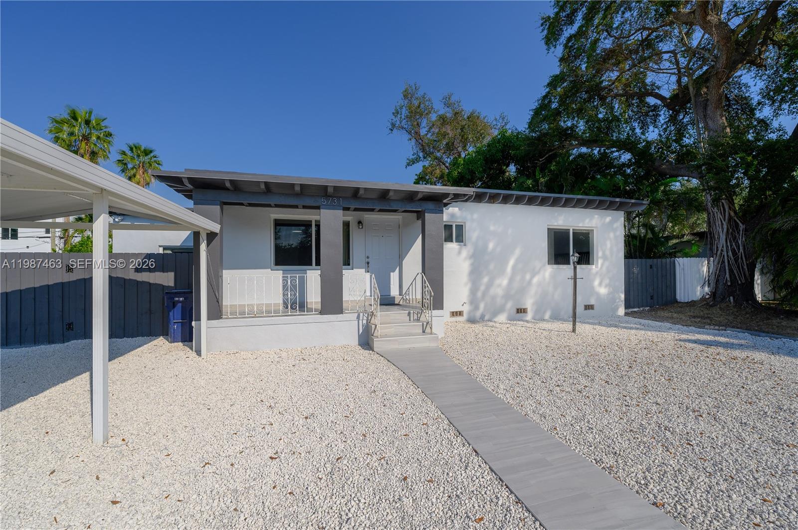 A single-story white house with a gray porch, gravel yard, and a covered carport — 5731 SW 62nd Ter, Miami FL 33143, MIAMI, FL