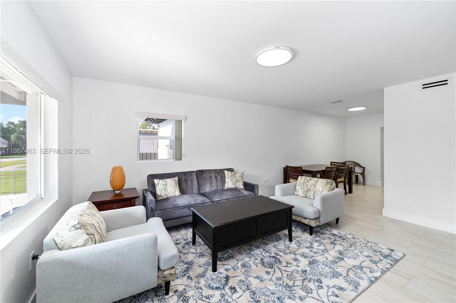 A living room features a grey sofa, two light-colored armchairs, and a dark coffee table — 5731 SW 62nd Ter, Miami FL 33143, MIAMI, FL