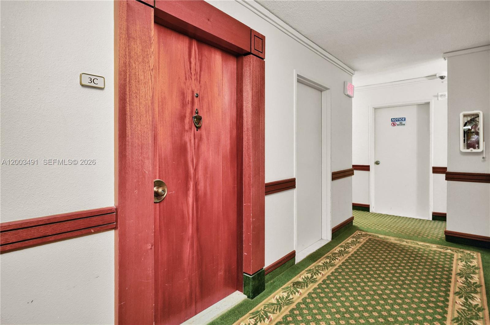 A hallway features a red wooden door labeled 3C, white walls, and green patterned carpeting — 5555 Collins Ave # 3C, Miami Beach FL 33140, MIAMI BEACH, FL