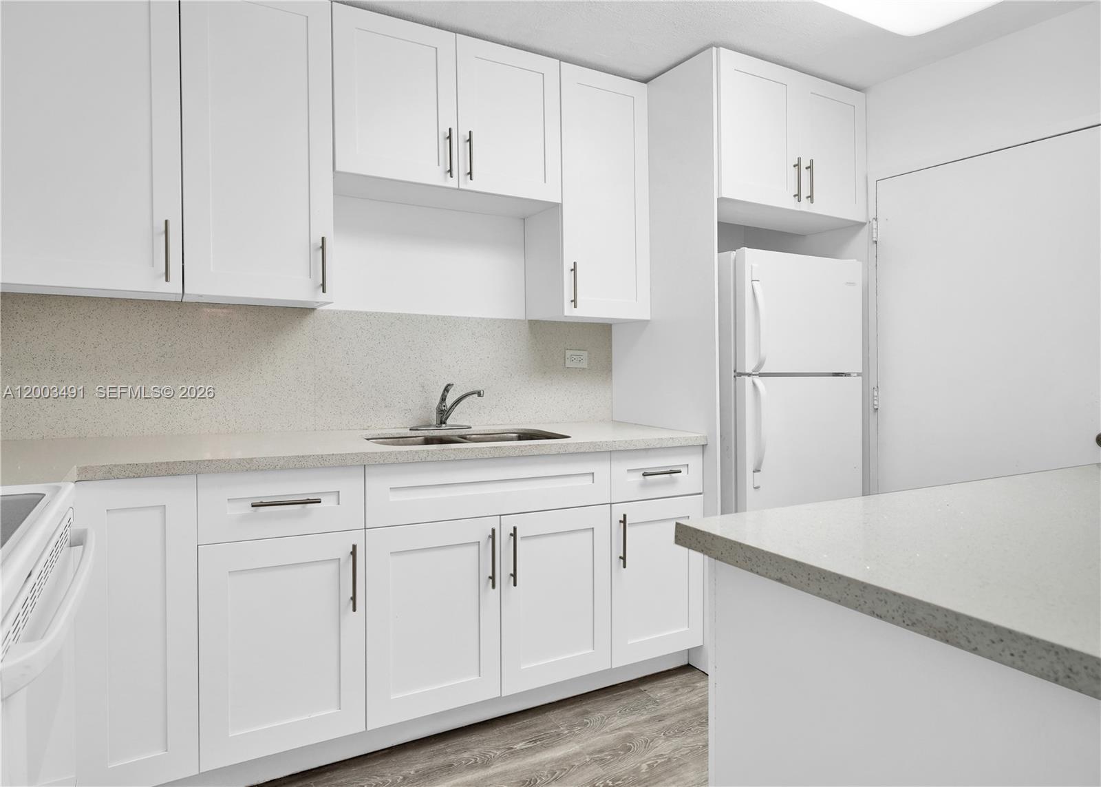 A kitchen features white cabinets, light gray countertops, a stainless steel sink, and white appliances — 5555 Collins Ave # 3C, Miami Beach FL 33140, MIAMI BEACH, FL