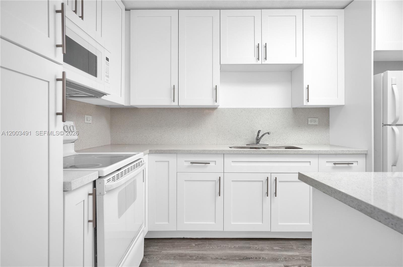 A bright kitchen features white cabinets, light countertops, and stainless steel appliances — 5555 Collins Ave # 3C, Miami Beach FL 33140, MIAMI BEACH, FL