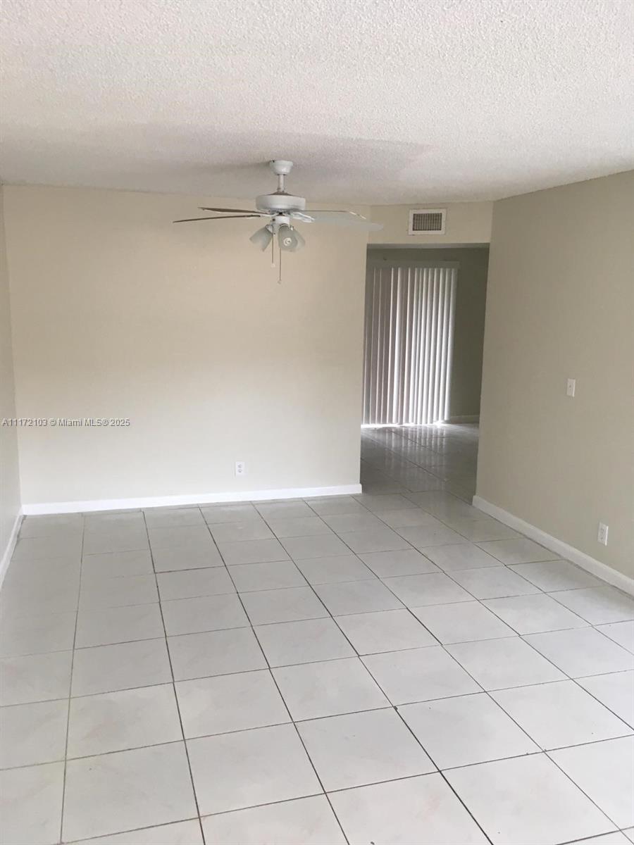 This room features light-colored tile flooring, a ceiling fan, and a doorway leading outside — 5962 NW 29th Pl # 112, Sunrise FL 33313, SUNRISE, FL
