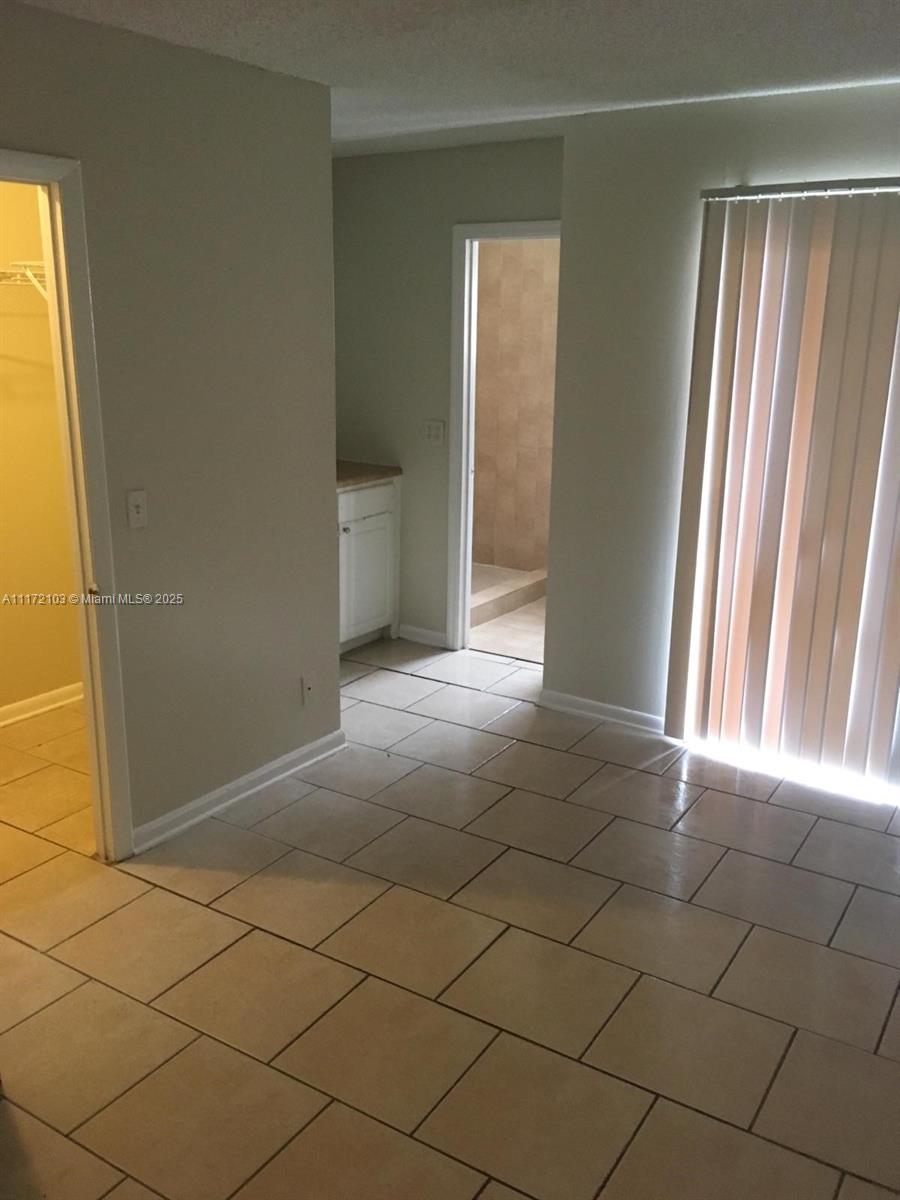 A room with light-colored tile flooring, a closet, a doorway to a bathroom, and vertical blinds — 5962 NW 29th Pl # 112, Sunrise FL 33313, SUNRISE, FL