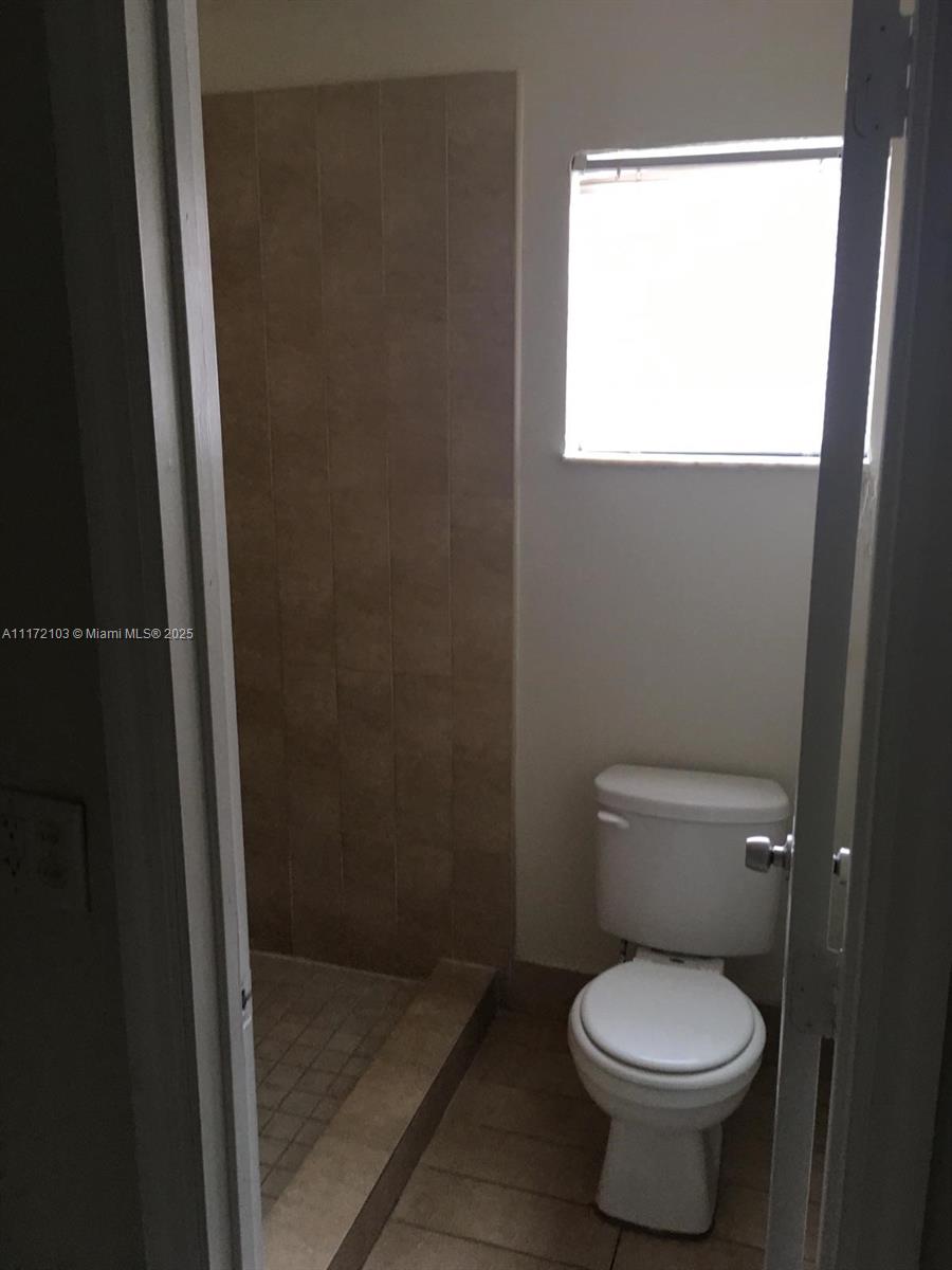 A bathroom features a tiled walk-in shower, a white toilet, and a window with blinds — 5962 NW 29th Pl # 112, Sunrise FL 33313, SUNRISE, FL