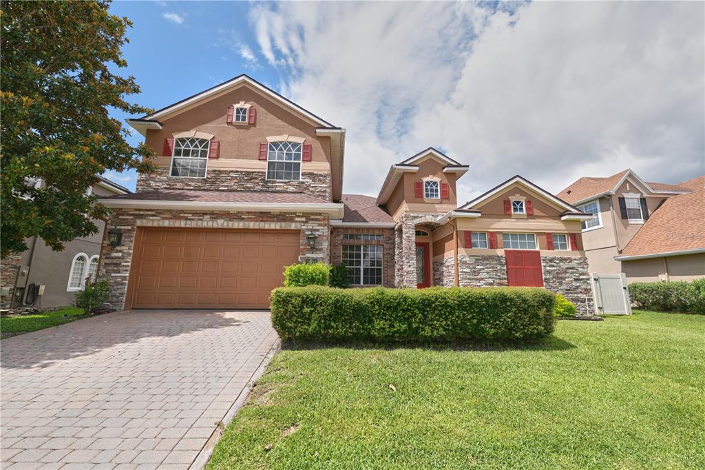 A two-story house with a stone facade, a two-car garage, and a manicured lawn — 5058 OTTERS DEN TRAIL, SANFORD, FL