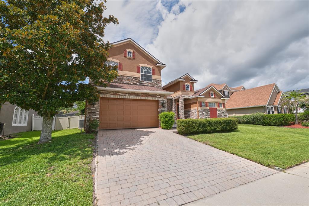 A two-story house with a stone facade, a two-car garage, and a paved driveway — 5058 OTTERS DEN TRAIL, SANFORD, FL