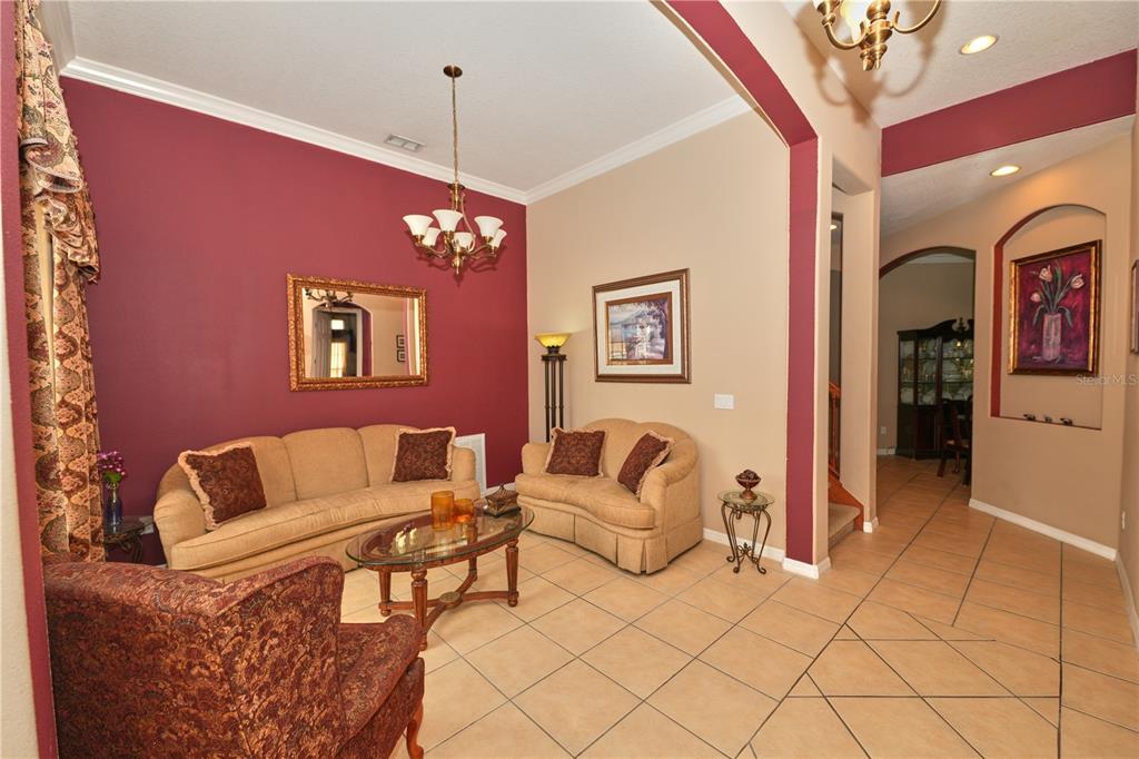 A living room features a red accent wall, beige sofas, tile flooring, and a chandelier — 5058 OTTERS DEN TRAIL, SANFORD, FL