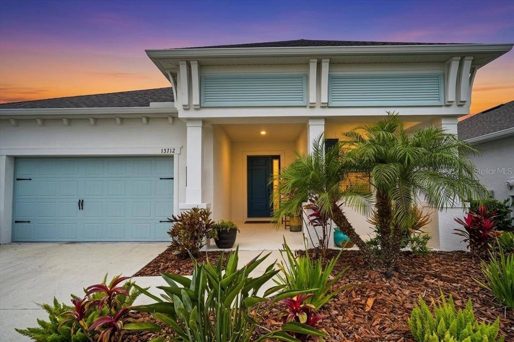 A single-story house with a light blue garage door, white exterior, and a palm tree — 13712 OLD CREEK COURT, PARRISH, FL