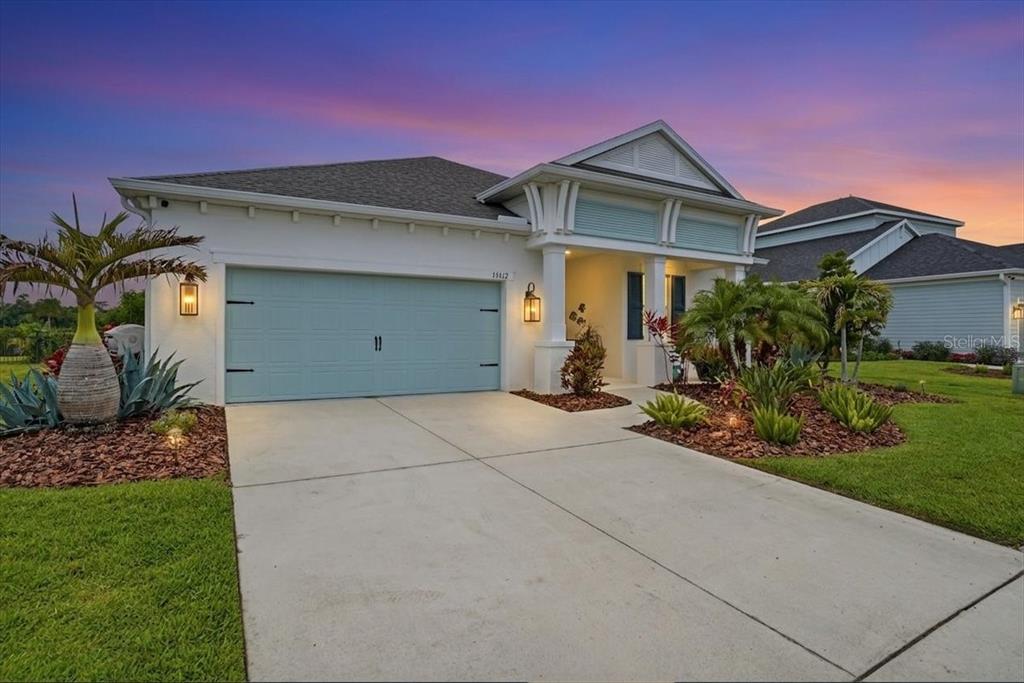 A single-story house with a light blue garage door and a concrete driveway at sunset — 13712 OLD CREEK COURT, PARRISH, FL