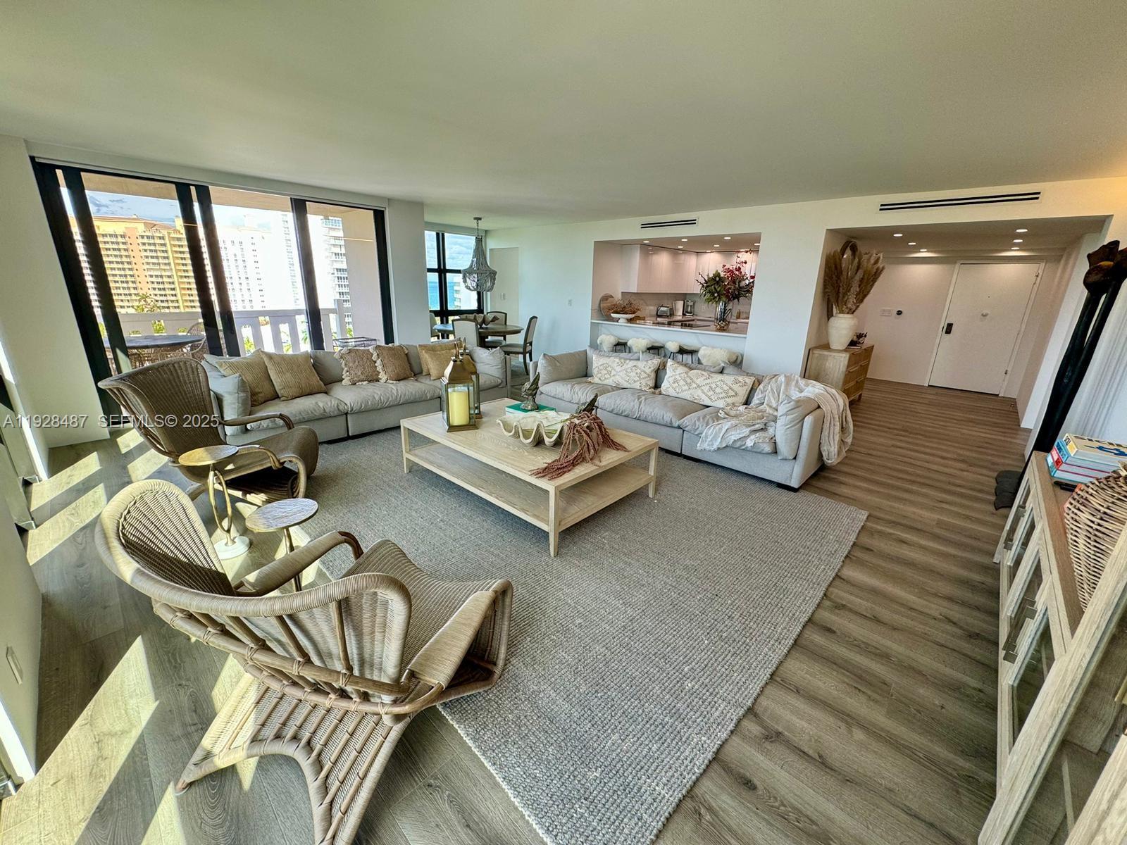 A spacious living room features light wood flooring, neutral furniture, and floor-to-ceiling windows with ocean views — 1121 Crandon Blvd # E1001, Key Biscayne FL 33149, KEY BISCAYNE, FL