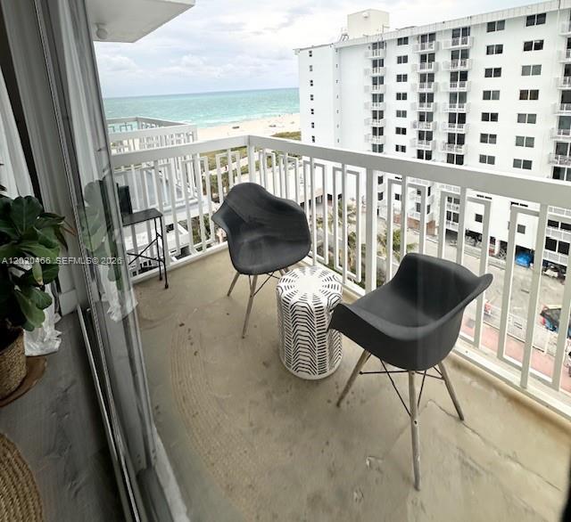 A balcony with two dark chairs and a patterned side table overlooks the ocean — 401 Ocean Dr # 910, Miami Beach FL 33139, MIAMI BEACH, FL
