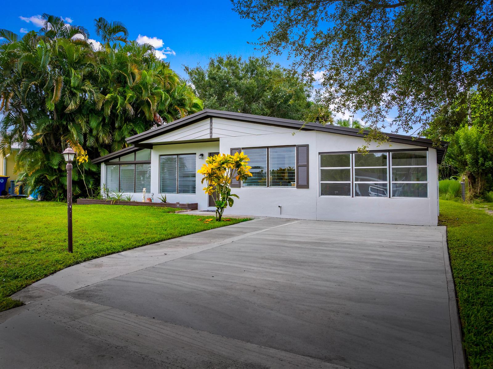 A single-story house with a white exterior, dark trim, and a concrete driveway — 2904 SE Bamboo Street, Stuart FL 34997, STUART, FL