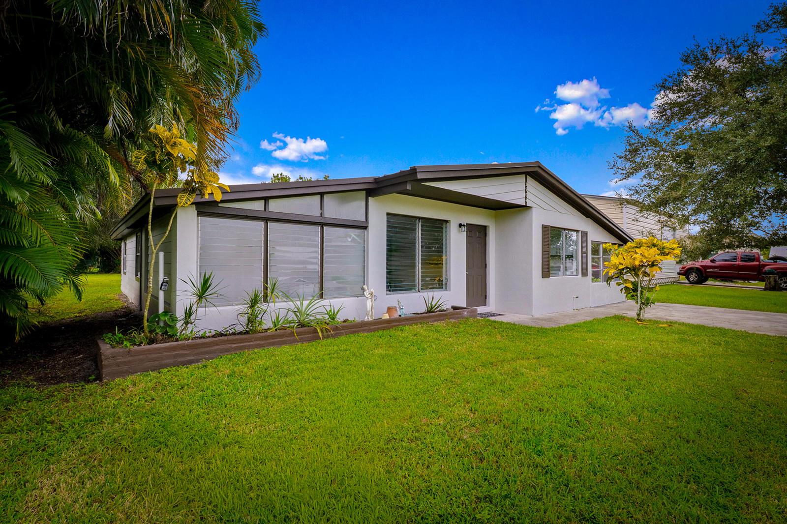 A single-story house with a white exterior, dark trim, and a large front window — 2904 SE Bamboo Street, Stuart FL 34997, STUART, FL