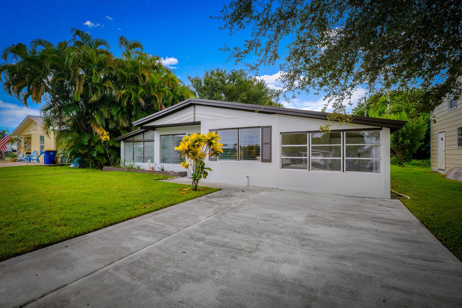 A single-story white house with a concrete driveway, large windows, and a grassy front yard — 2904 SE Bamboo Street, Stuart FL 34997, STUART, FL