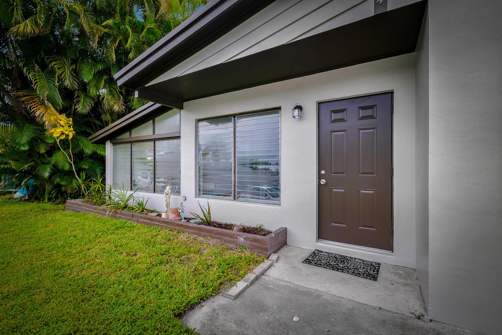 A brown front door and windows with horizontal blinds on a white exterior house wall — 2904 SE Bamboo Street, Stuart FL 34997, STUART, FL
