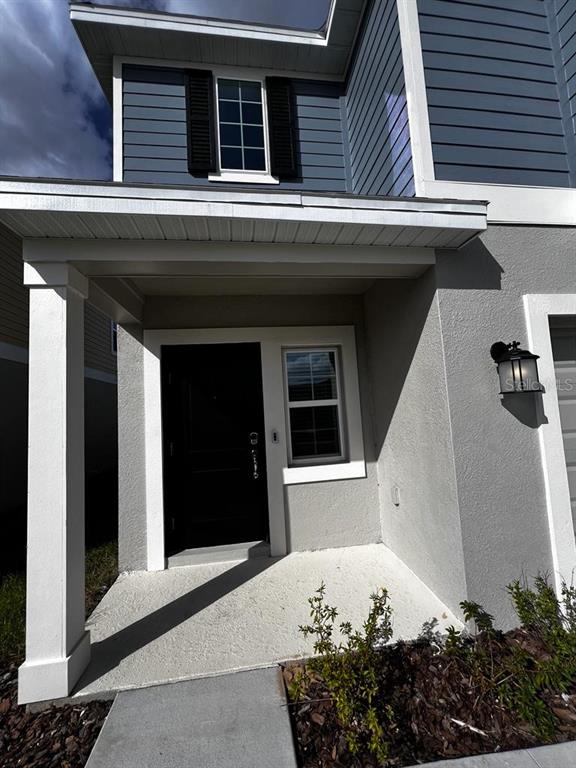 The exterior of a house features a covered entryway with a black door and siding — 215 AQUA AVENUE, DAVENPORT, FL