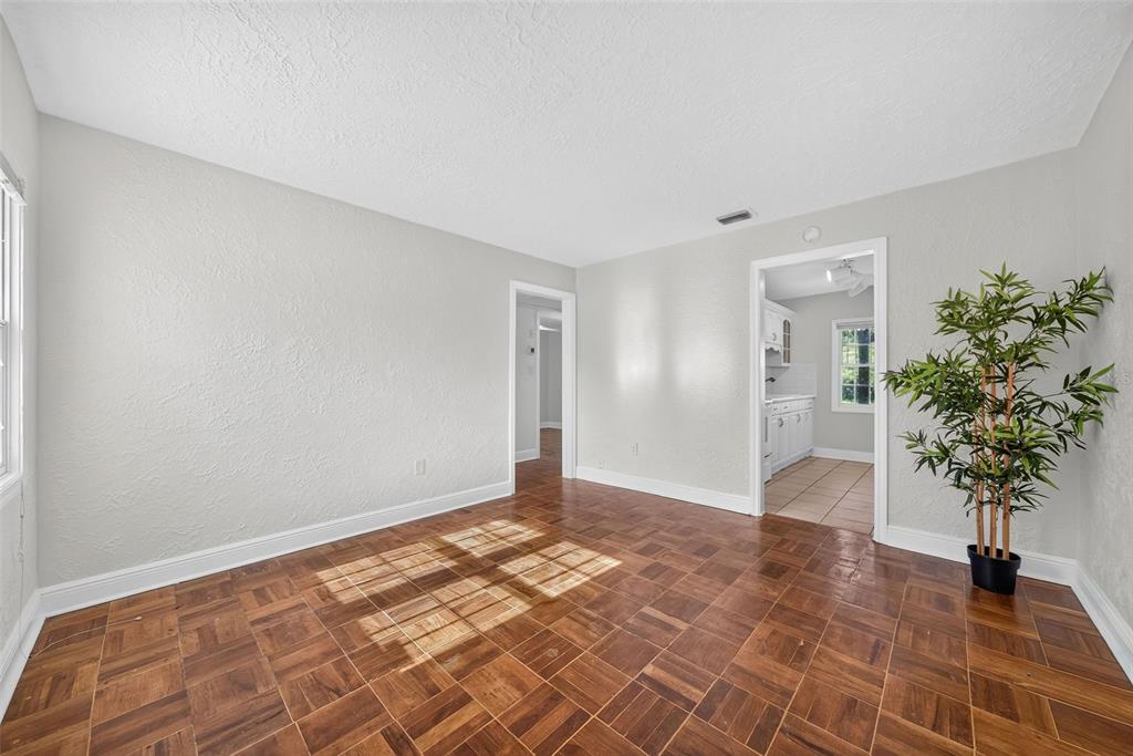An empty room features parquet wood flooring, light gray walls, and a potted artificial plant — 1333 S DENNING DRIVE, WINTER PARK, FL