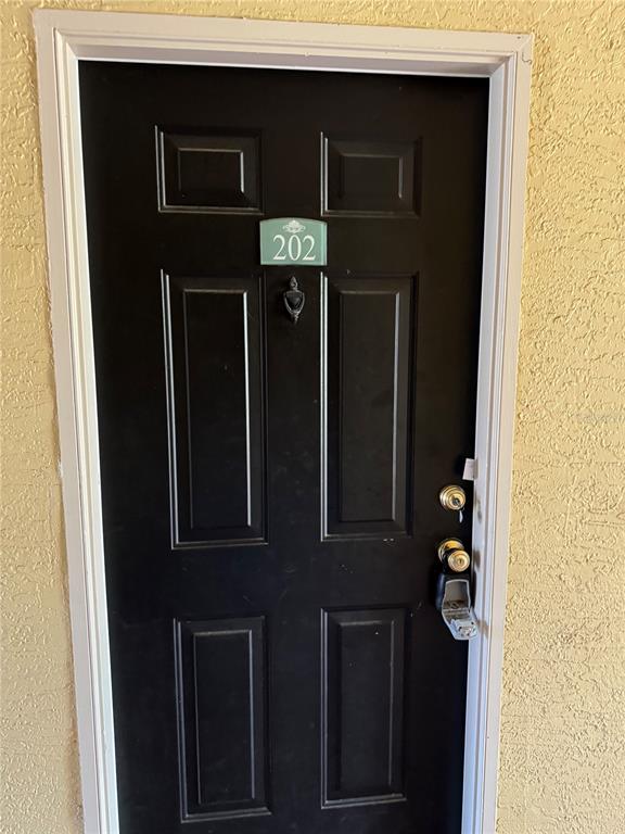 A black front door with a room number sign and a lockbox on the handle — 1920 SUMMER CLUB DRIVE UNIT 202, OVIEDO, FL