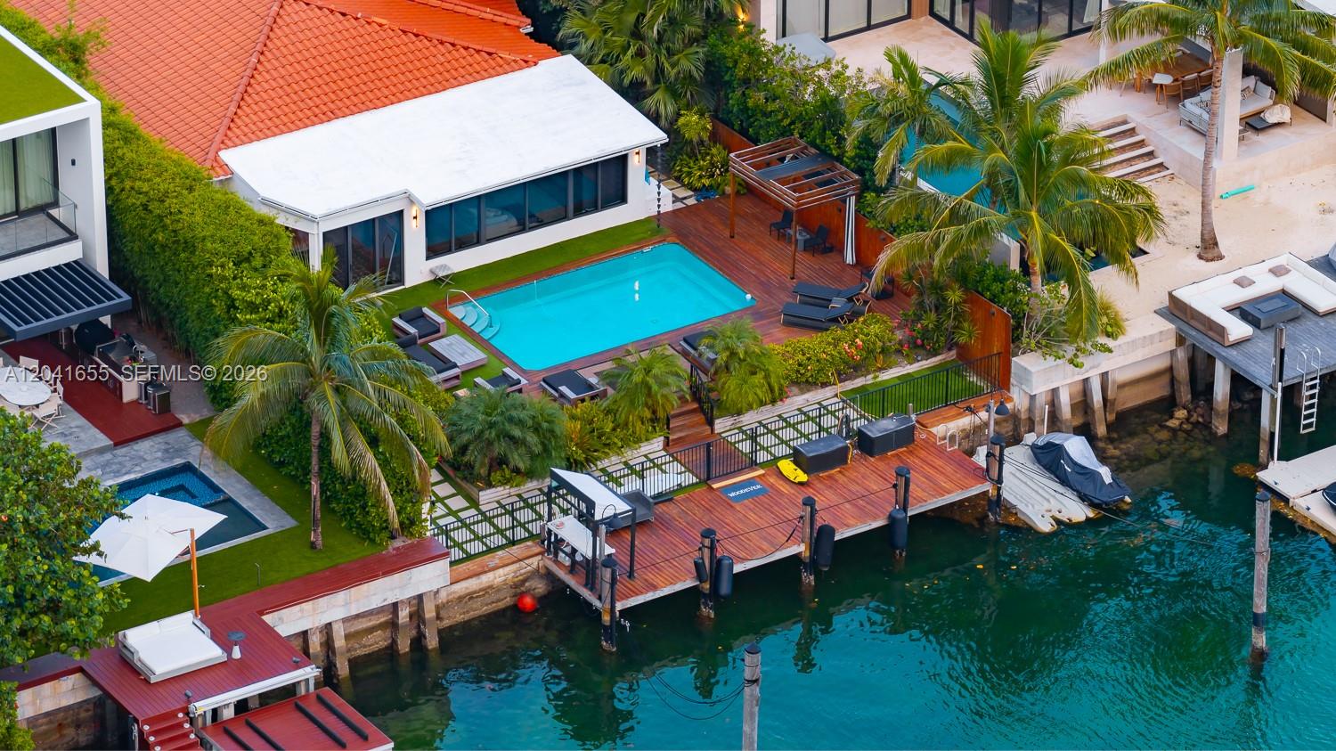 An aerial view shows a waterfront home with a swimming pool, wooden deck, and dock — 460 W Dilido Dr, Miami Beach FL 33139, MIAMI BEACH, FL