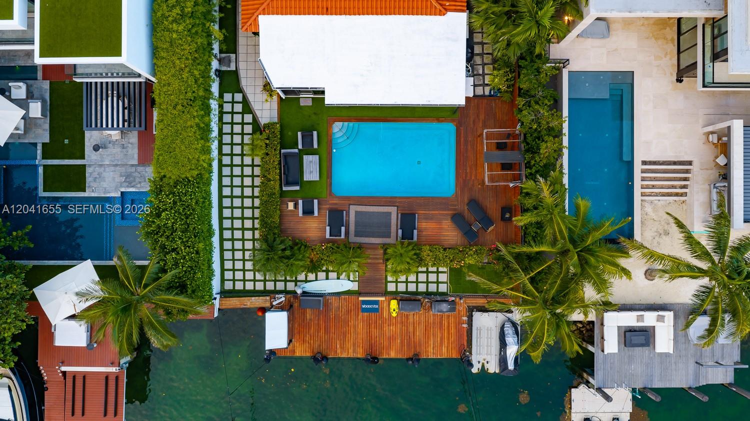 An aerial view shows a waterfront property with a swimming pool, wooden deck, and dock — 460 W Dilido Dr, Miami Beach FL 33139, MIAMI BEACH, FL