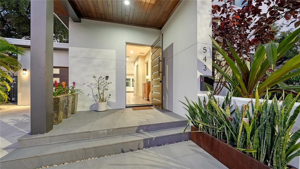 The exterior entrance features a modern wooden door, tiled steps, and potted plants — 543 COLUMBIA COURT, SARASOTA, FL