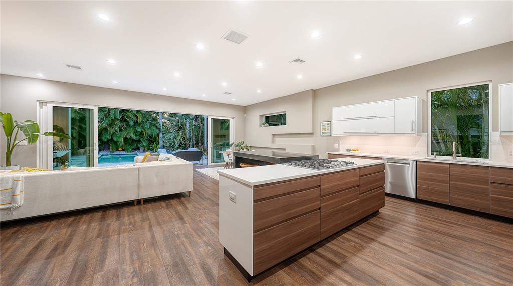 A modern open-concept kitchen and living area features wood cabinetry, a large island, and sliding doors — 543 COLUMBIA COURT, SARASOTA, FL