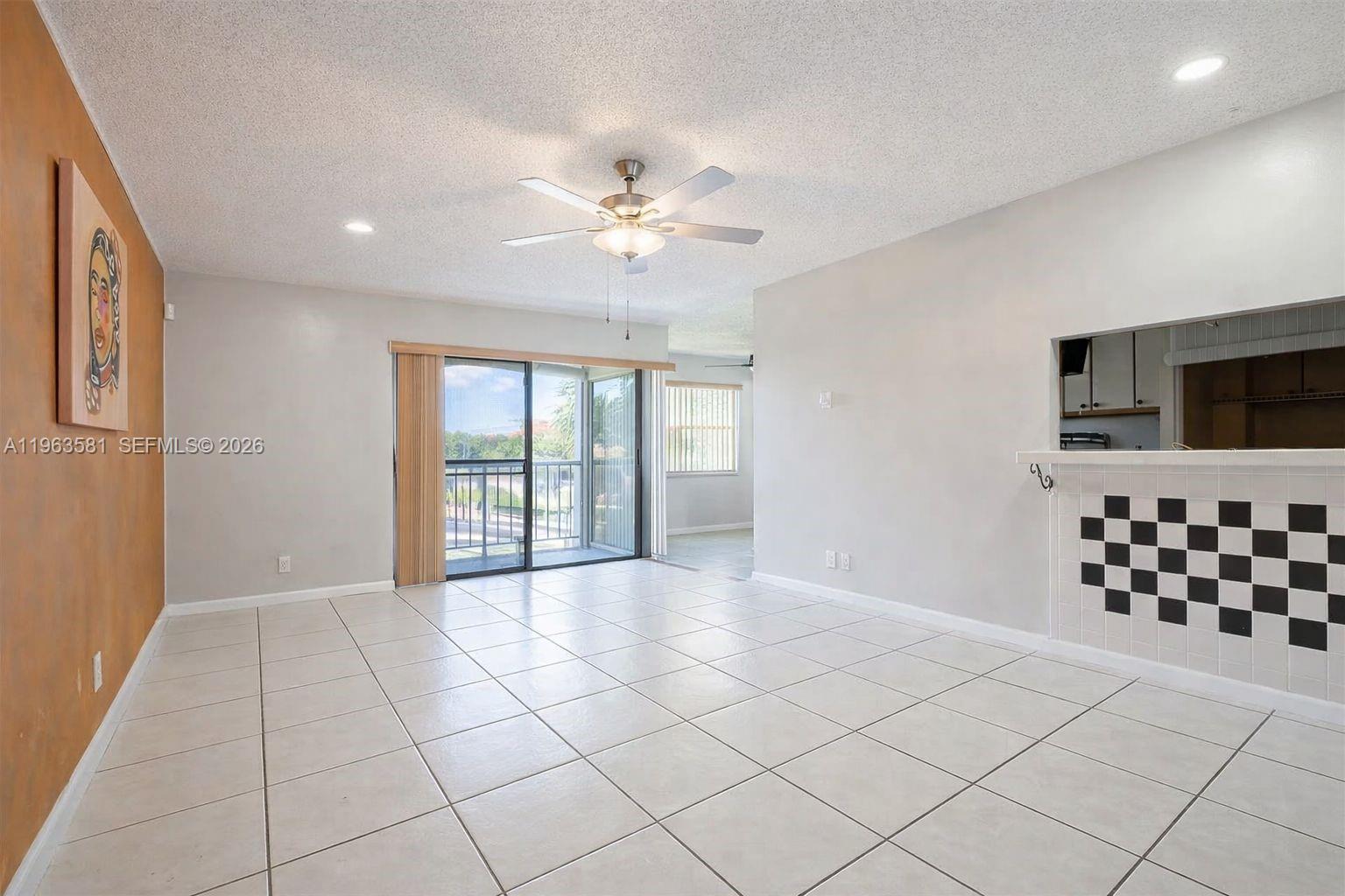 A living room features light tile flooring, a ceiling fan, and a checkered tile counter — 2075 NW 46th Ave # I201, Lauderhill FL 33313, LAUDERHILL, FL